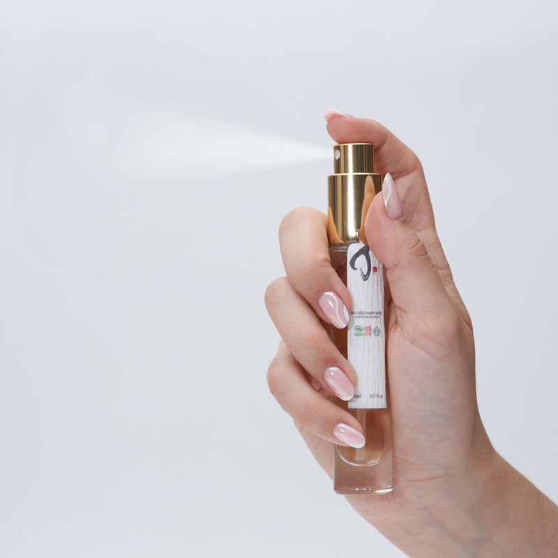 main de femme appuyant sur la brume parfumée