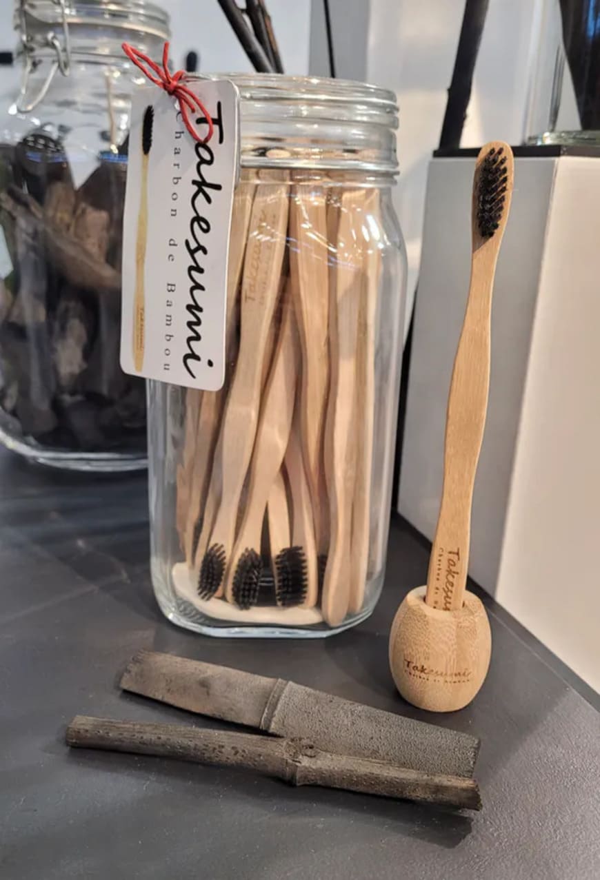bocal avec brosses à dents en bambou et brosse à dents posée sur un porte brosse à dents